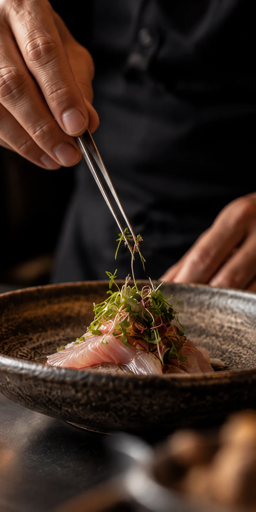 A chef placing delicate herbs on a carefully prepared dish